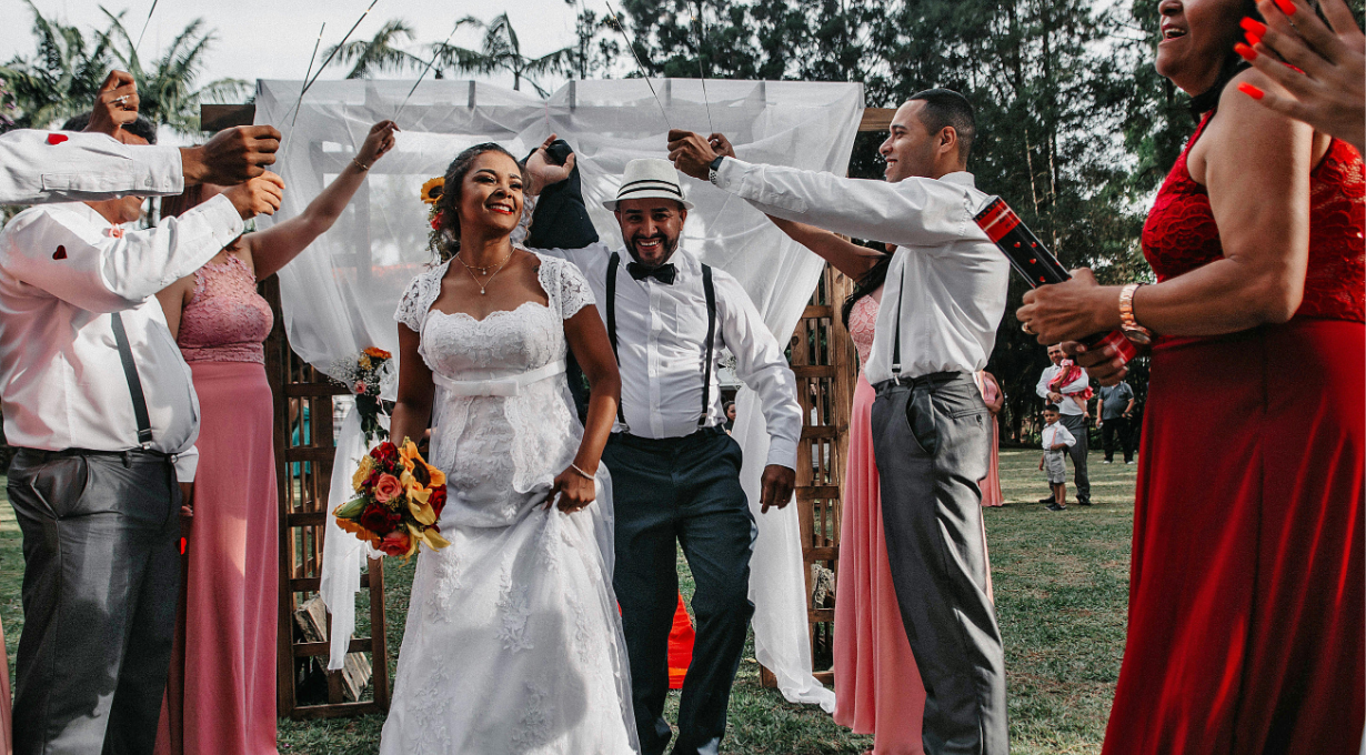 A couple walking and friends laughing and sharing wedding wishes at reception
