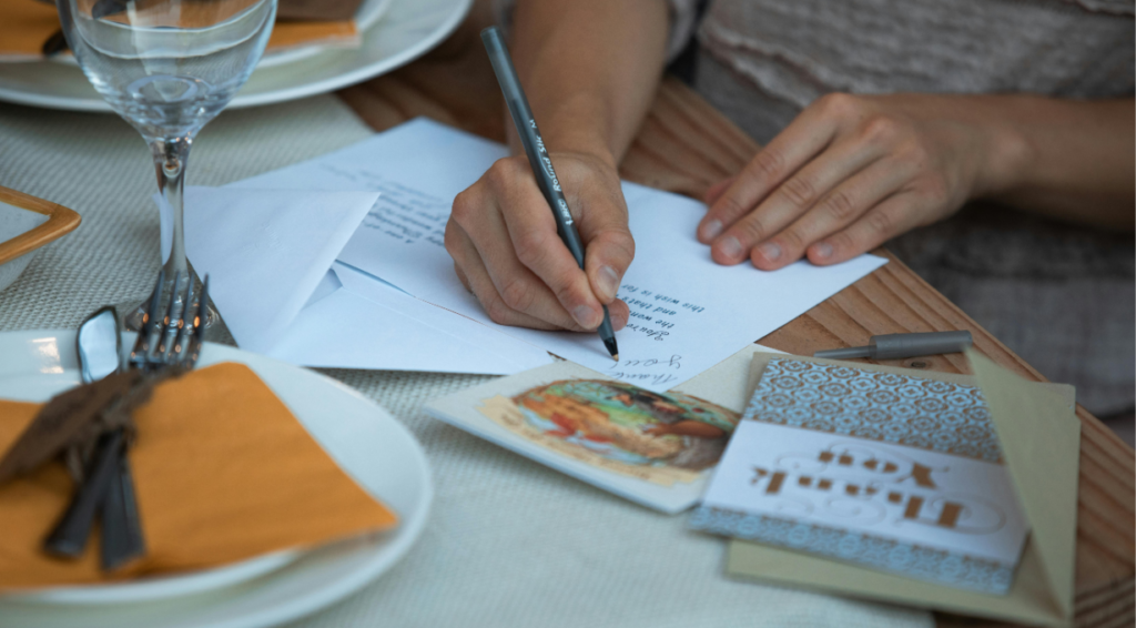 A woman writing a heartfelt birthday wish to read aloud at a sweet sixteen candle ceremony